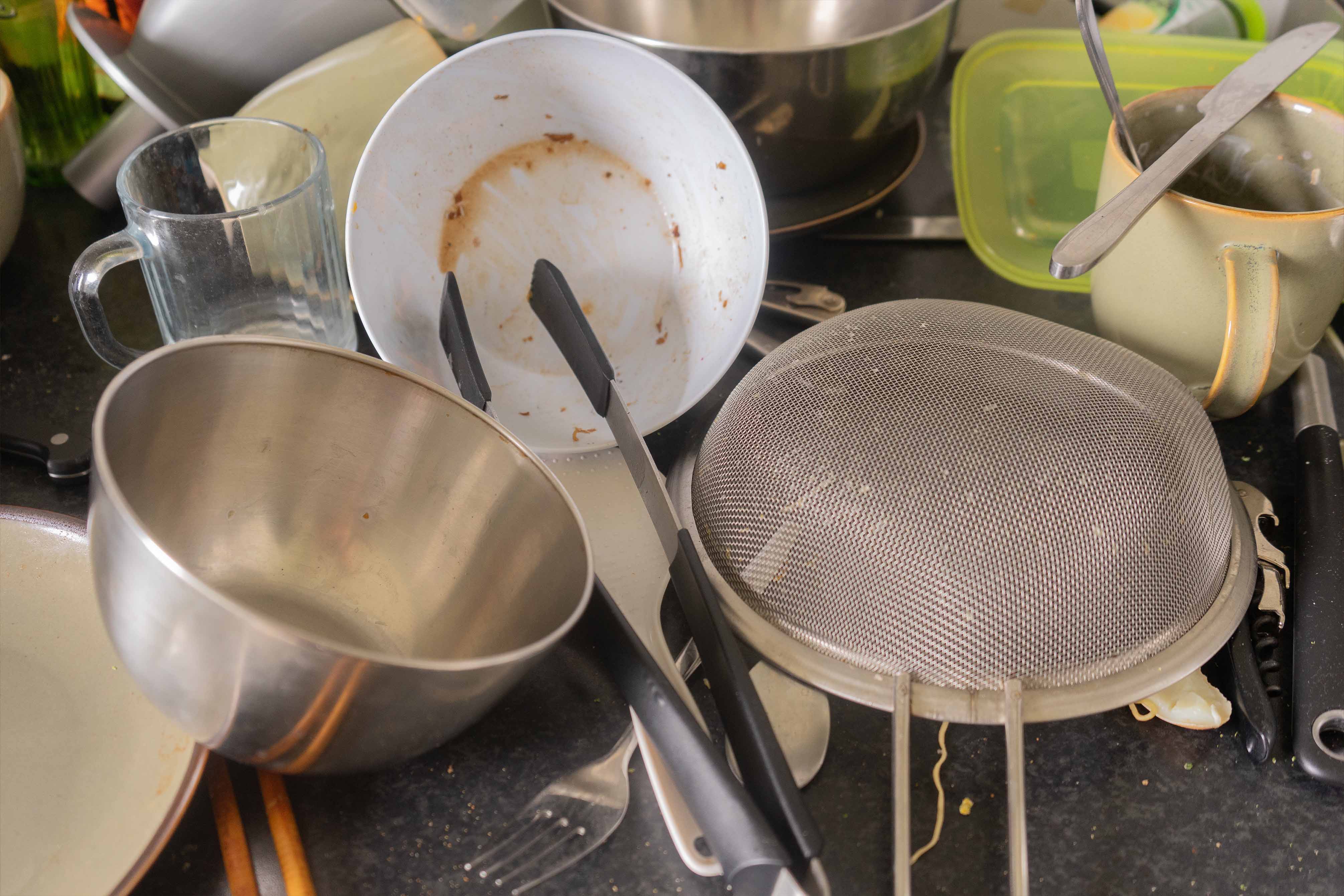 A messy restaurant sink full of dirty unwashed dishes 