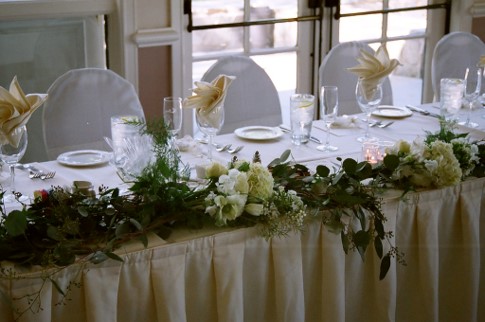 The head table at a wedding, beautifully decorated with flowers, fine glassware, and dinnerware 