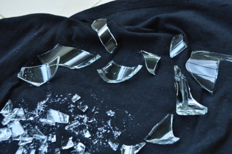 A broken glass laying in a pile on top of a black tablecloth