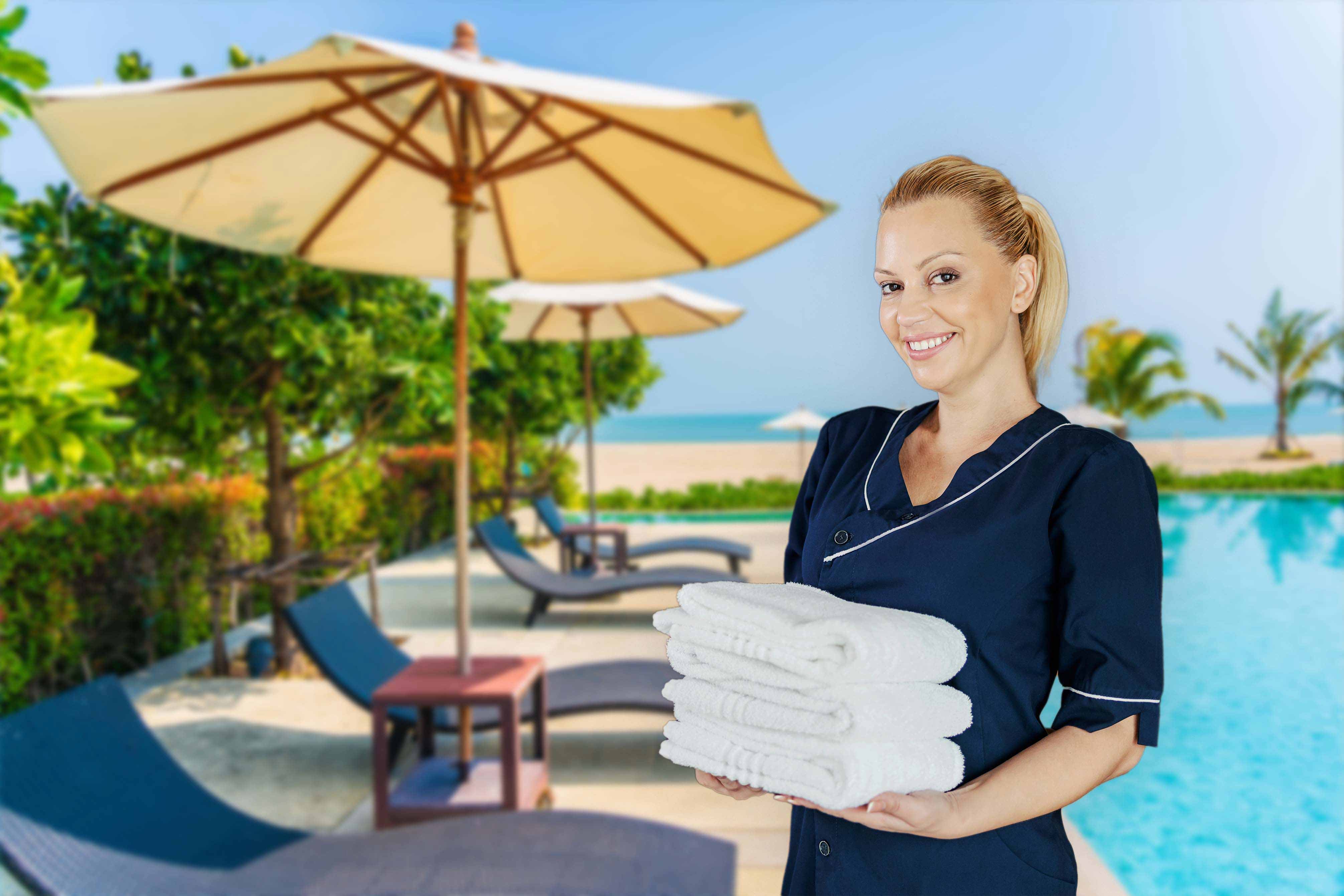 Resort staff posing with a bundle of towels poolside that are being delivered to guests
